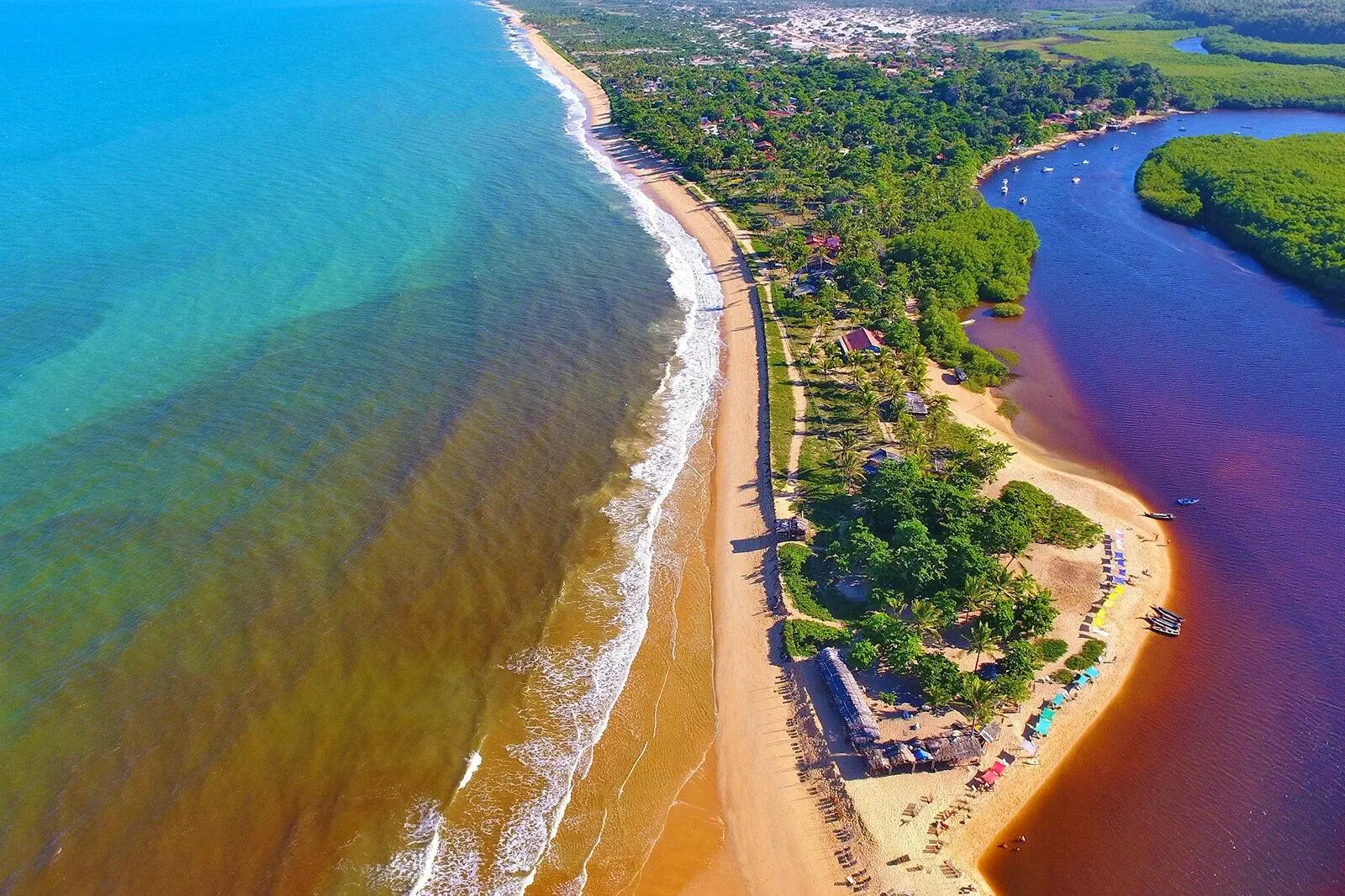 Vista aérea de Caraíva, na Bahia, com a vila, o rio e o mar