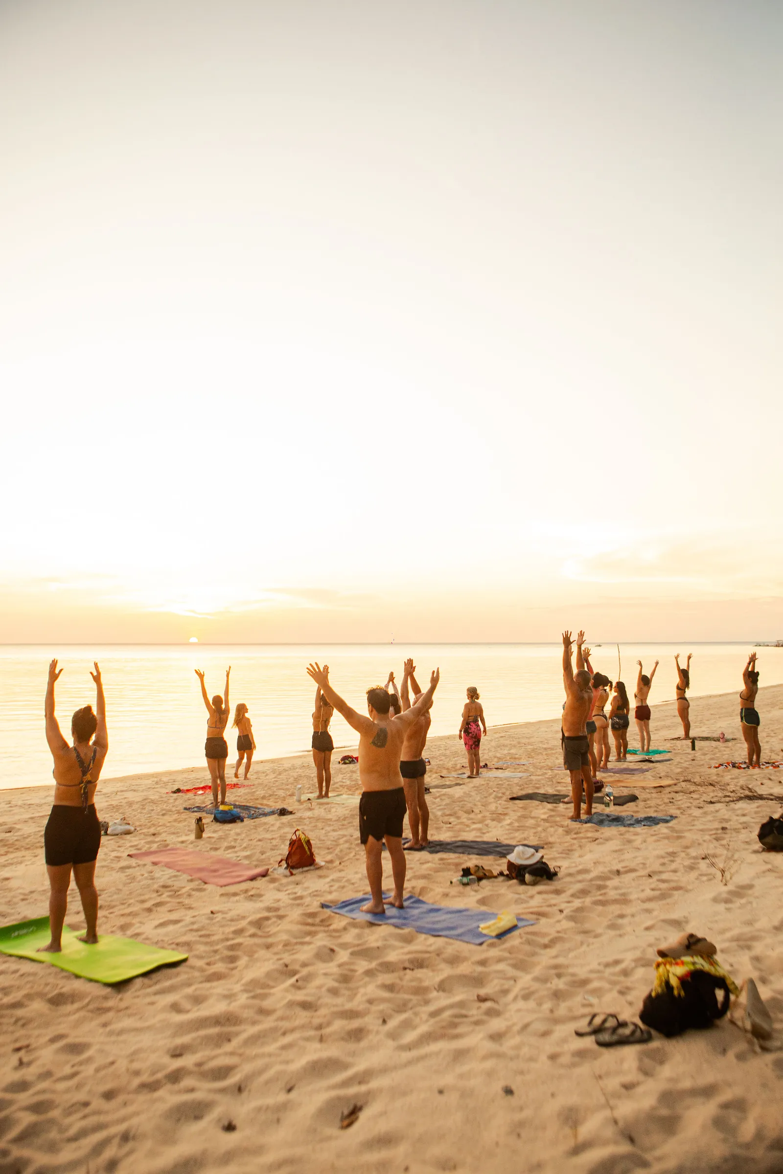 Aula de yoga na praia, com a professora orientando os participantes