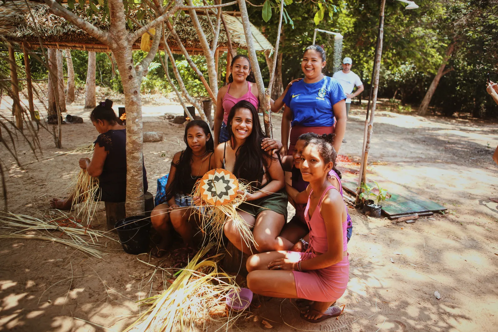 Grupo com artesãs e peças de fibras naturais na comunidade