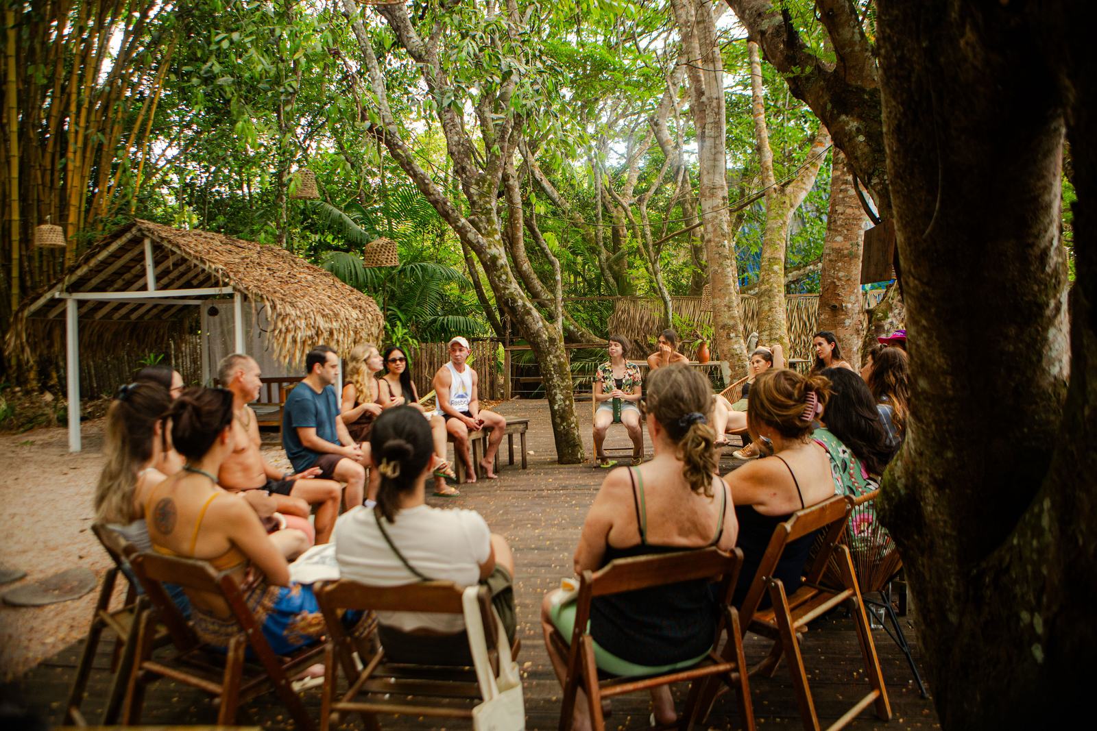 Grupo de viajantes sentado em roda de conversa sob as árvores durante uma jornada